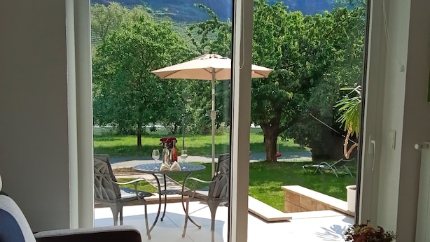 A modern living room with a sofa, a glass coffee table, and a view of an outdoor patio area with a table and chairs.