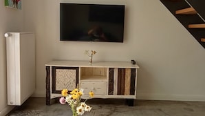 A modern living room with a wooden coffee table, a TV mounted on the wall, and a staircase.