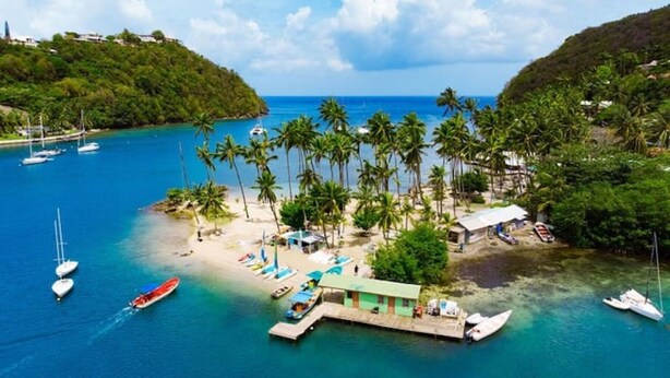 Eine tropische Insel mit Strand, Palmen und Booten.