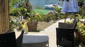 Eine Terrasse mit Korbmöbeln, einem Blumentopf und Blick auf einen Yachthafen mit Booten.