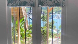 Eine weiße Tür mit gebogenem oberen Rand und Blick auf ein blaues Gewässer durch das Fenster.