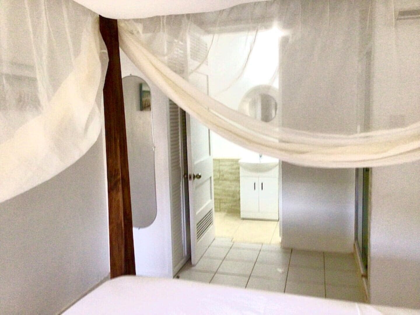 A bedroom with a bed, a door, and a bathroom visible through an open door.
