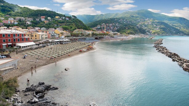 Une ville côtière dotée d’une plage, de bâtiments et bordée par une chaîne de montagnes.