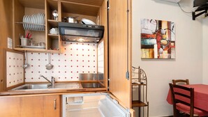 Une cuisine compacte dotée d’un évier intégré, d’un four à micro-ondes et d’un coin repas avec une table et des chaises.
