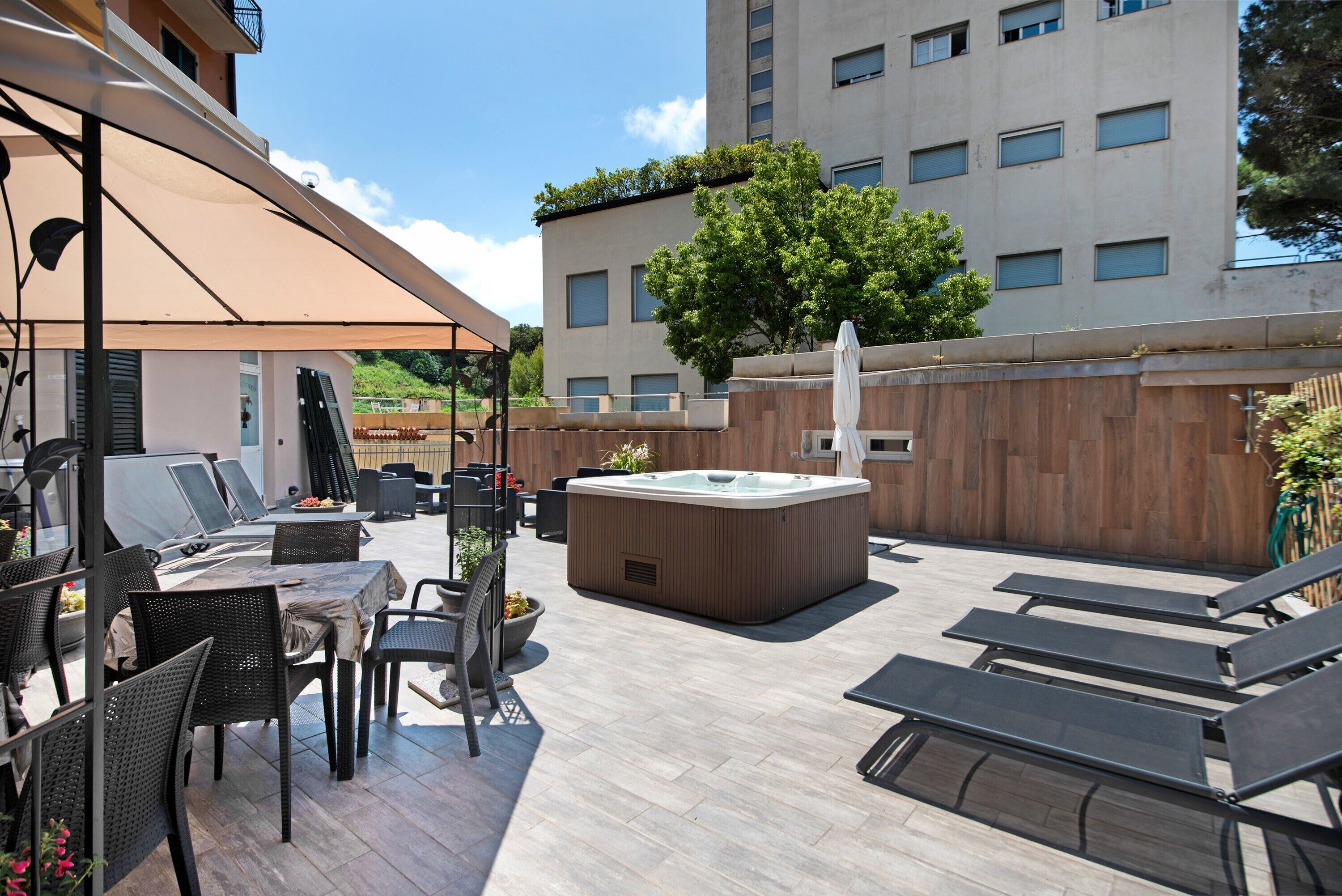 An outdoor patio with a hot tub, lounge chairs, and a covered dining area.