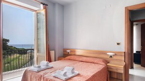 A bedroom with a bed, a bedside table, a nightstand, a window with a view, and a door. - Apartment 'Residence Paradiso Bilocale 202' with Sea View, Wi-Fi and Air Conditioning (Moneglia)