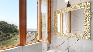 A bathroom with a large window, a marble sink, and a gold-framed mirror. - Apartment 'Residence Paradiso Bilocale 202' with Sea View, Wi-Fi and Air Conditioning (Moneglia)