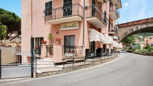 A hotel named 'Paradiso' with a balcony, outdoor seating, and a stone bridge in the background. - Apartment 'Residence Paradiso Bilocale 202' with Sea View, Wi-Fi and Air Conditioning (Moneglia)
