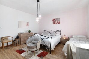 Een slaapkamer met een bed, twee stoelen, een kaptafel, een nachtkastje en een hanglamp.