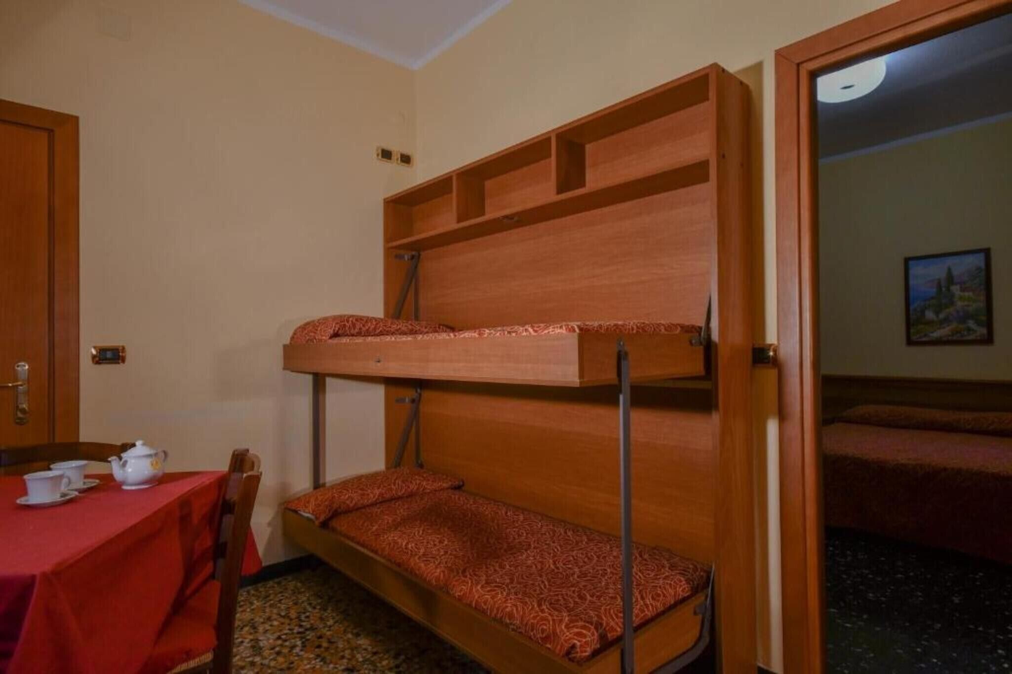Een stapelbed met een tafel, stoelen, een deur en een schilderij aan de muur.