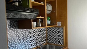 A compact kitchen with a tiled backsplash, a built-in sink, and wooden cabinetry. - Apartment 'Residence Paradiso Bilocale 203' with Balcony, Wi-Fi and Air Conditioning (Moneglia)