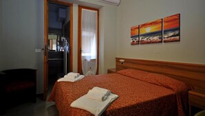 A hotel room with a bed, a mirror, a door, and a wall with three paintings. - Apartment 'Residence Paradiso Bilocale 203' with Balcony, Wi-Fi and Air Conditioning (Moneglia)