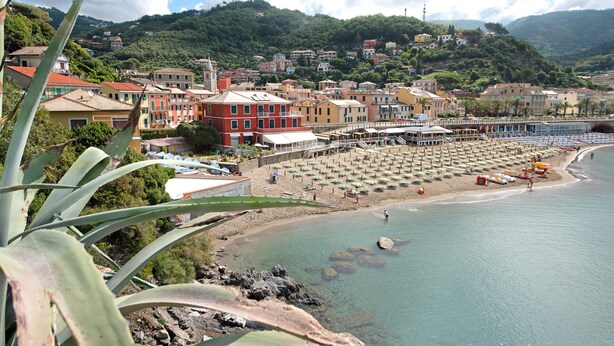 A coastal town with buildings, a beach, and a rocky shoreline.