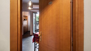 A wooden door with a number plate, a dining area with a red tablecloth, and a hanging light fixture. - Apartment 'Residence Paradiso Bilocale 304' with Balcony, Wi-Fi and Air Conditioning (Moneglia)