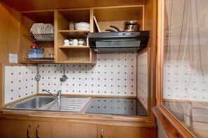 A compact kitchen with a sink, stove, and wooden cabinets.