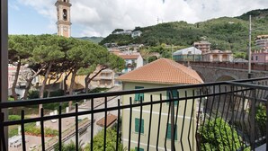 A balcony with a view of a town, including a clock tower, residential buildings, and greenery. - Apartment 'Residence Paradiso Bilocale 304' with Balcony, Wi-Fi and Air Conditioning (Moneglia)