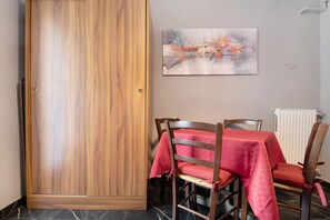 A dining area with a wooden door, a table with a red tablecloth, and a chair with a red cushion.