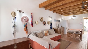 A cozy living area with a sofa, wooden beams, wall decorations, and a dining table. - Holiday Home 'Ana Townhouse' with Private Terrace, Wi-Fi and Air Conditioning (Tavira)