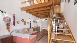A room with a wooden staircase, a sofa, a wooden dresser, and a dining area. - Holiday Home 'Ana Townhouse' with Private Terrace, Wi-Fi and Air Conditioning (Tavira)