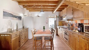 A wooden kitchen with a dining table, chairs, cabinets, and a hanging light fixture. - Holiday Home 'Ana Townhouse' with Private Terrace, Wi-Fi and Air Conditioning (Tavira)