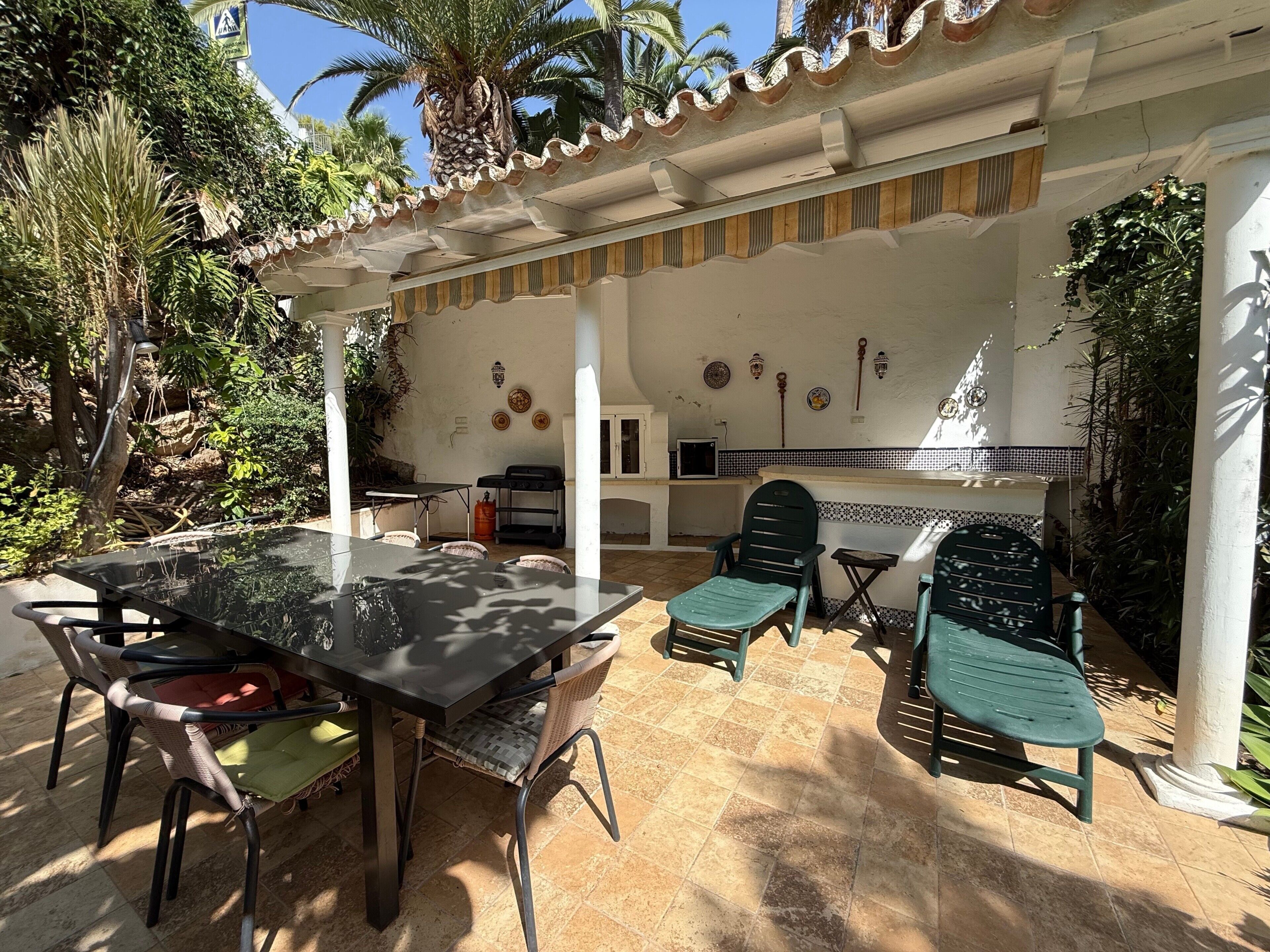 An outdoor patio with a table and chairs, a grill, and a tiled backsplash.