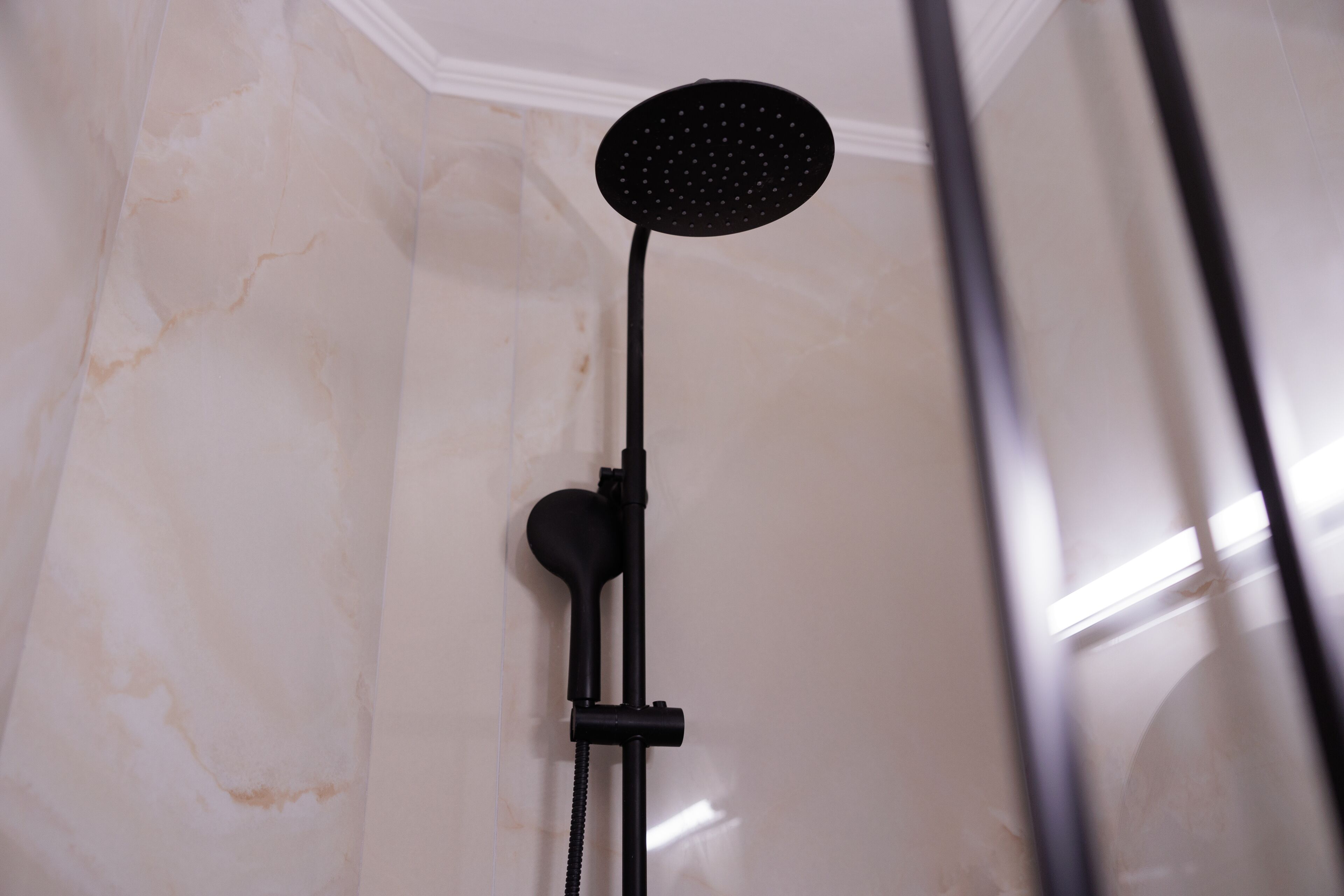Een moderne douche met een handdouche aan de wand.
