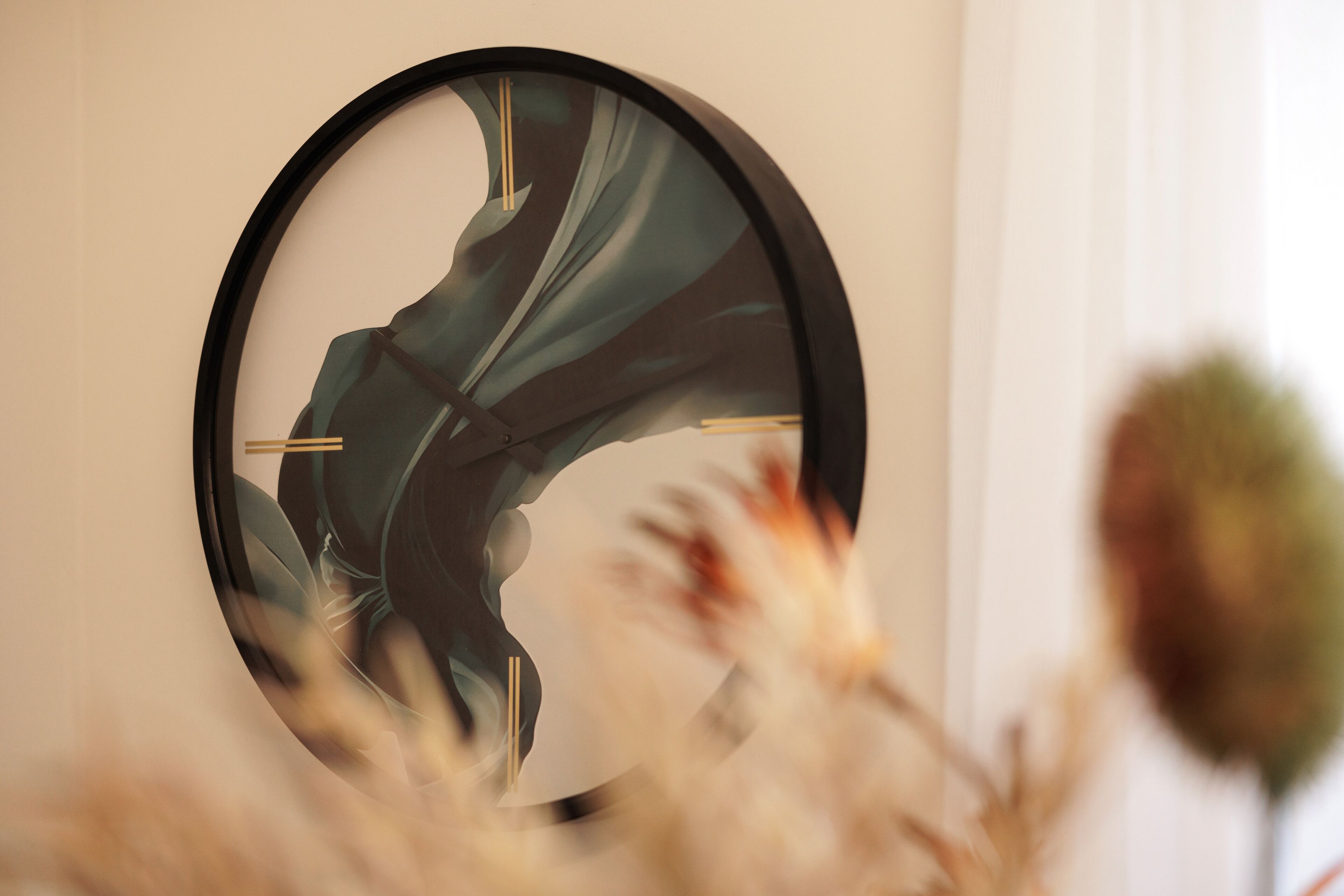 A round wall clock with a modern design, mounted on a plain wall.