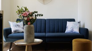 Un salon moderne avec un canapé bleu, un vase à motifs décoré de fleurs et une table ronde.