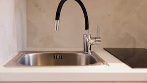 Un évier de cuisine doté d’un robinet moderne, d’un bac en acier inoxydable et d’un plan de travail noir.