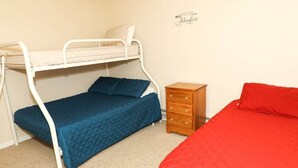 A bunk bed with a lower bunk, a wooden nightstand, and a red bed.