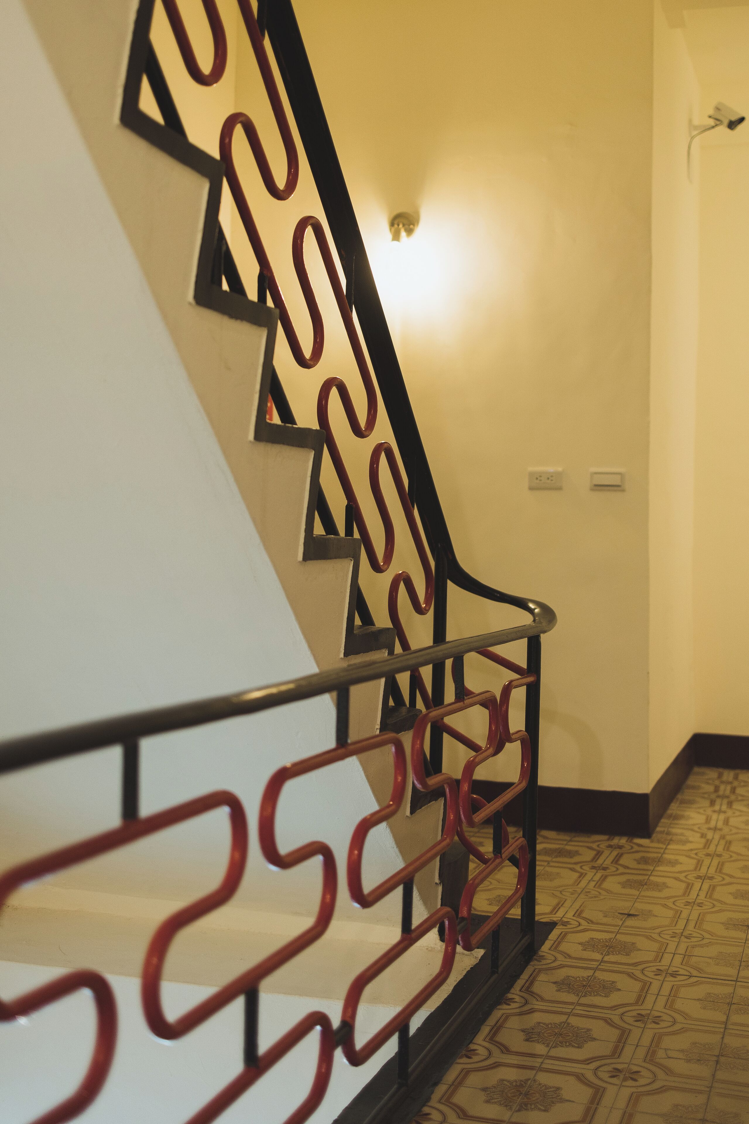 Una escalera con barandilla de metal de diseño geométrico y baldosas de suelo con estampado.