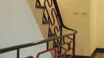 Una escalera con barandilla de metal de diseño geométrico y baldosas de suelo con estampado.