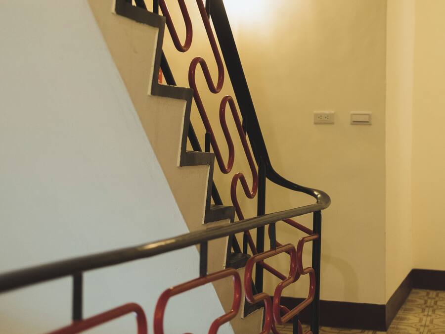 Una escalera con barandilla de metal de diseño geométrico y baldosas de suelo con estampado.