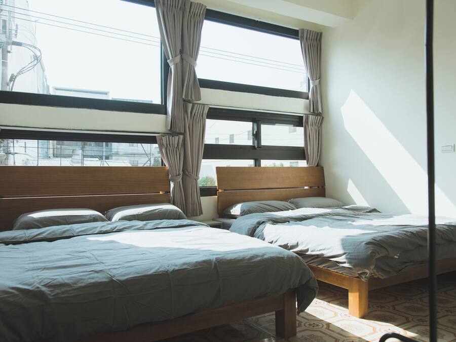 A bedroom with two beds, large windows, and a view of the city.