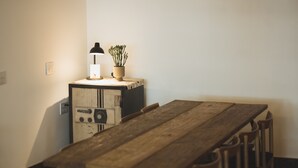 Een houten eettafel met stoelen, een lamp en een potplant op een klein kastje.