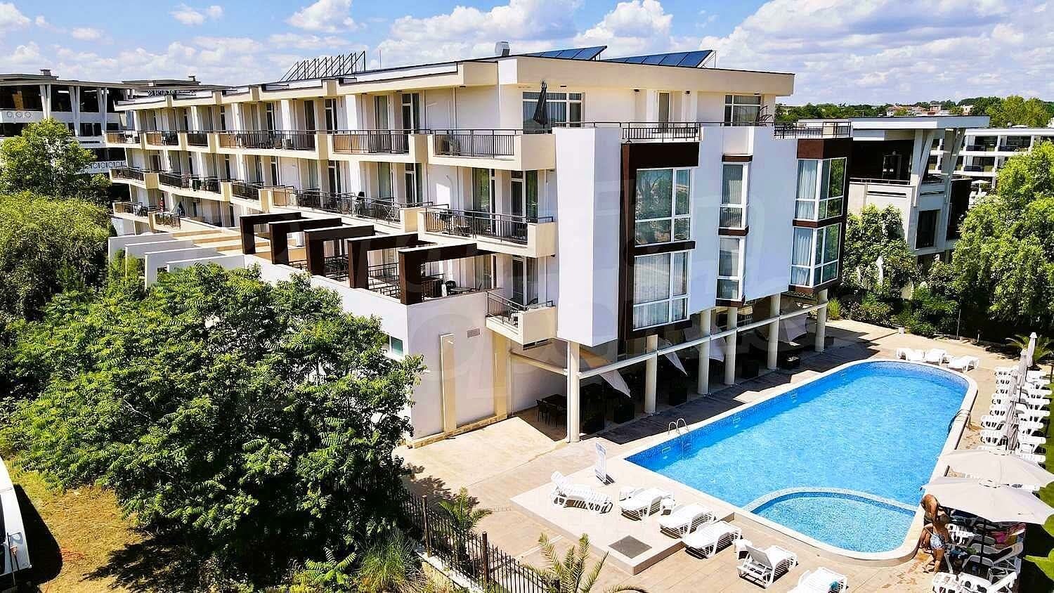 A modern hotel with multiple floors, a swimming pool, and outdoor seating.