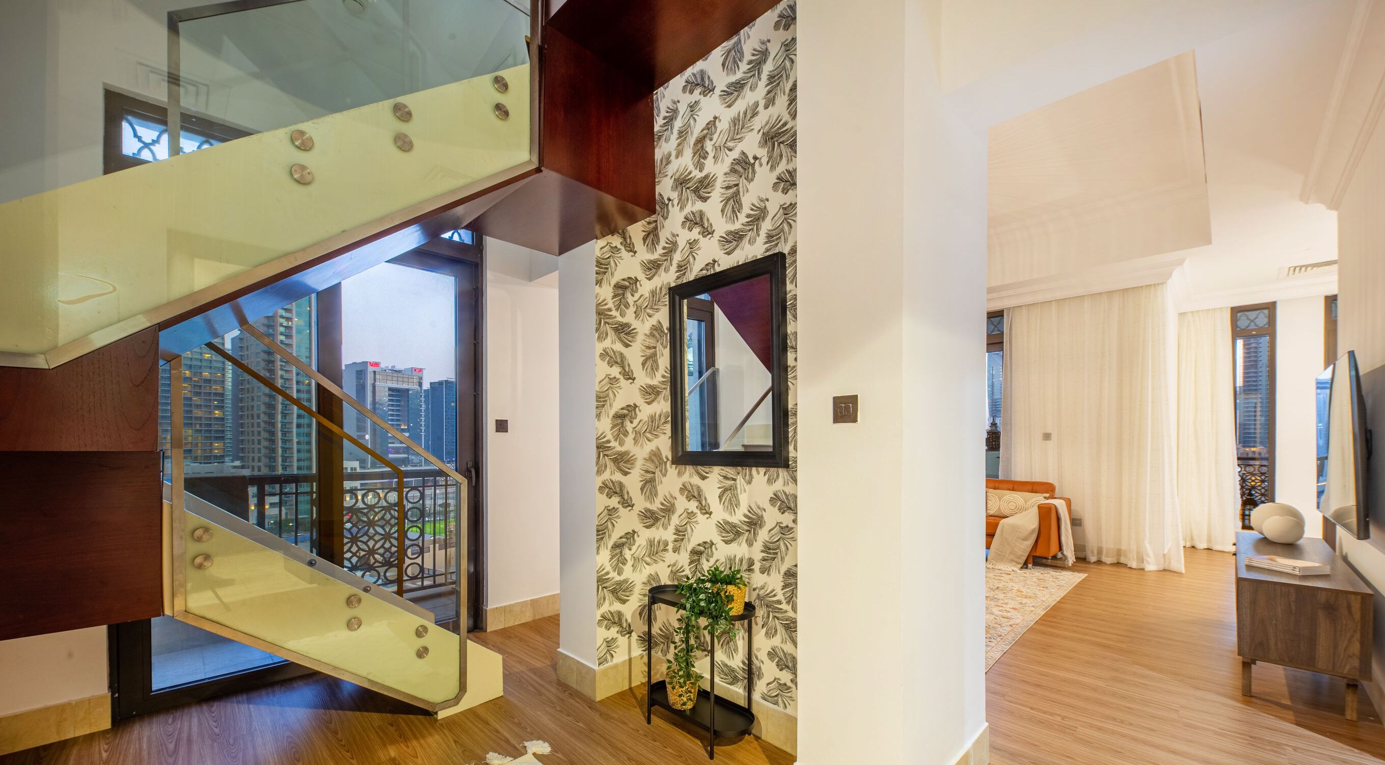 Un intérieur moderne avec un escalier, un mur orné de motifs et une vue sur la ville.