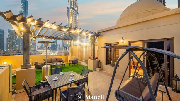 Eine Dachterrasse mit Außenmöbeln, einer Pergola mit Lichterketten und einem Schaukelstuhl.