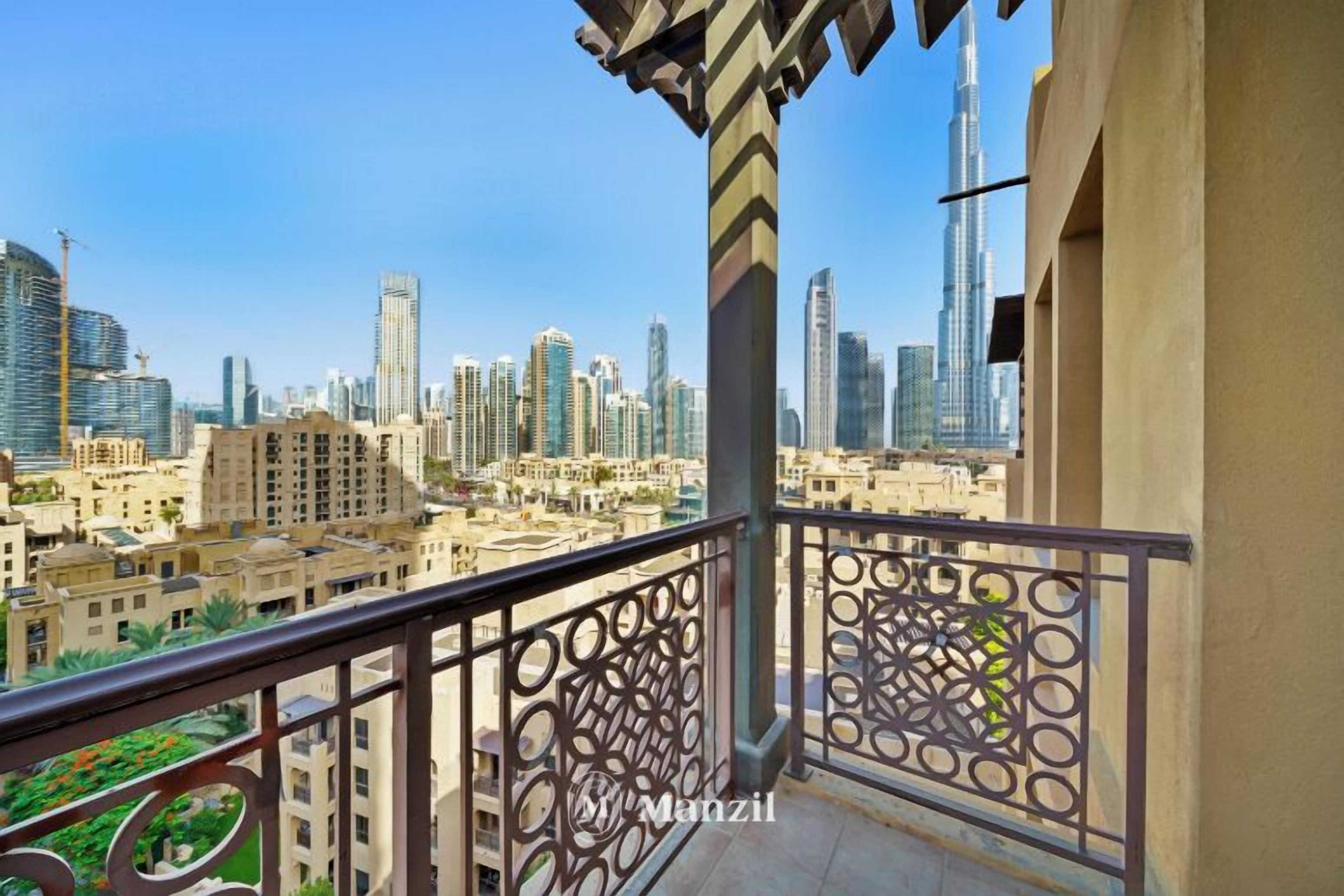 A balcony with a view of a cityscape, including high-rise buildings and a clear sky.