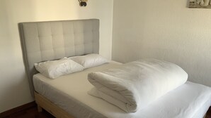 A single bed with a grey headboard, white bedding, and a wooden frame. - Cozy room near Metro Station, close to  Airport  , easy access to city center (Lisboa)
