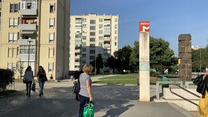 A pedestrian area with a metro sign, a tall building, and a green park. - Cozy room near Metro Station, close to  Airport  , easy access to city center (Lisboa)