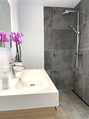 A modern bathroom with a white sink, a handheld showerhead, and a potted orchid. - Close to the Lovely Beach, Copenhagen, Roskilde and Køge (Karlslunde)