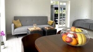 Ein modernes Wohnzimmer mit einem grauen Sofa, einem Holztisch und einer Glasschale mit Obst.