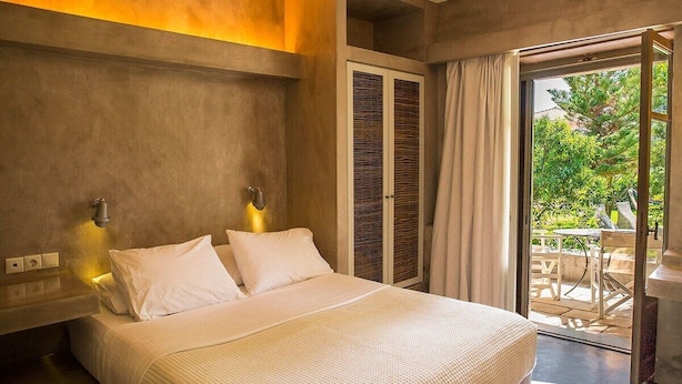 A bedroom with a bed, two bedside lamps, a window with curtains, and a view of the outdoors. - Stavlos Cottage - Apartment Ground Floor 1 (Lefkada)