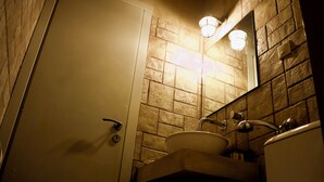 A bathroom with a stone wall, a sink, a mirror, and a toilet. - Stavlos Cottage - Apartment Ground Floor 1 (Lefkada)