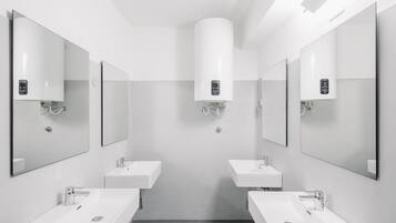 Un baño moderno con dos lavamanos, espejos y un radiador central.