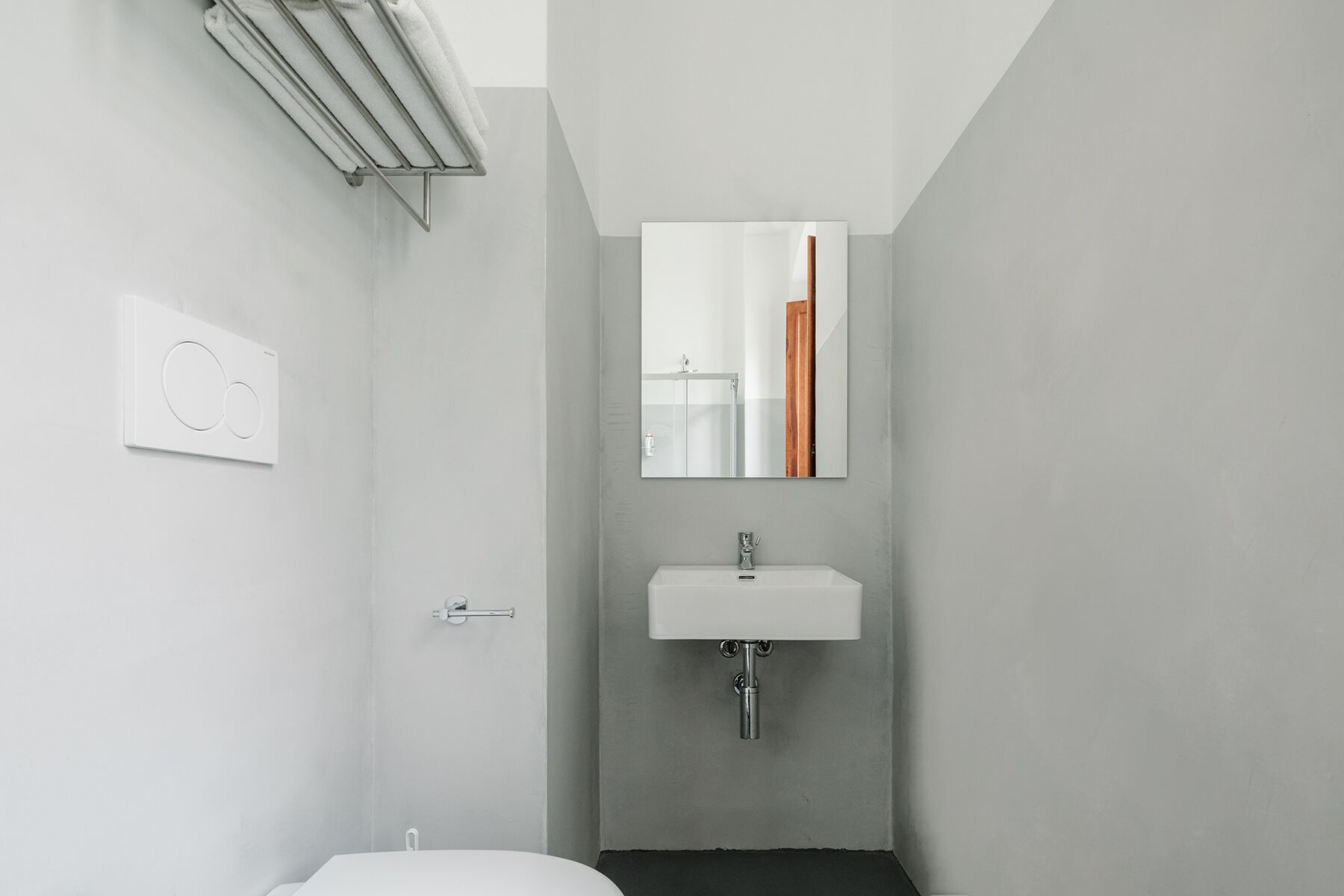 Ein modernes Badezimmer mit einem weißen Waschbecken, einem Handtuchhalter und einem Spiegel.