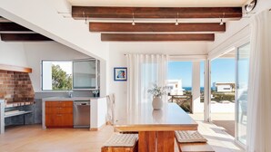 A modern kitchen with a brick wall, wooden cabinets, and a large island. - Villa Mercedes - Warm and quiet villa without equal (Ciutadella de Menorca)