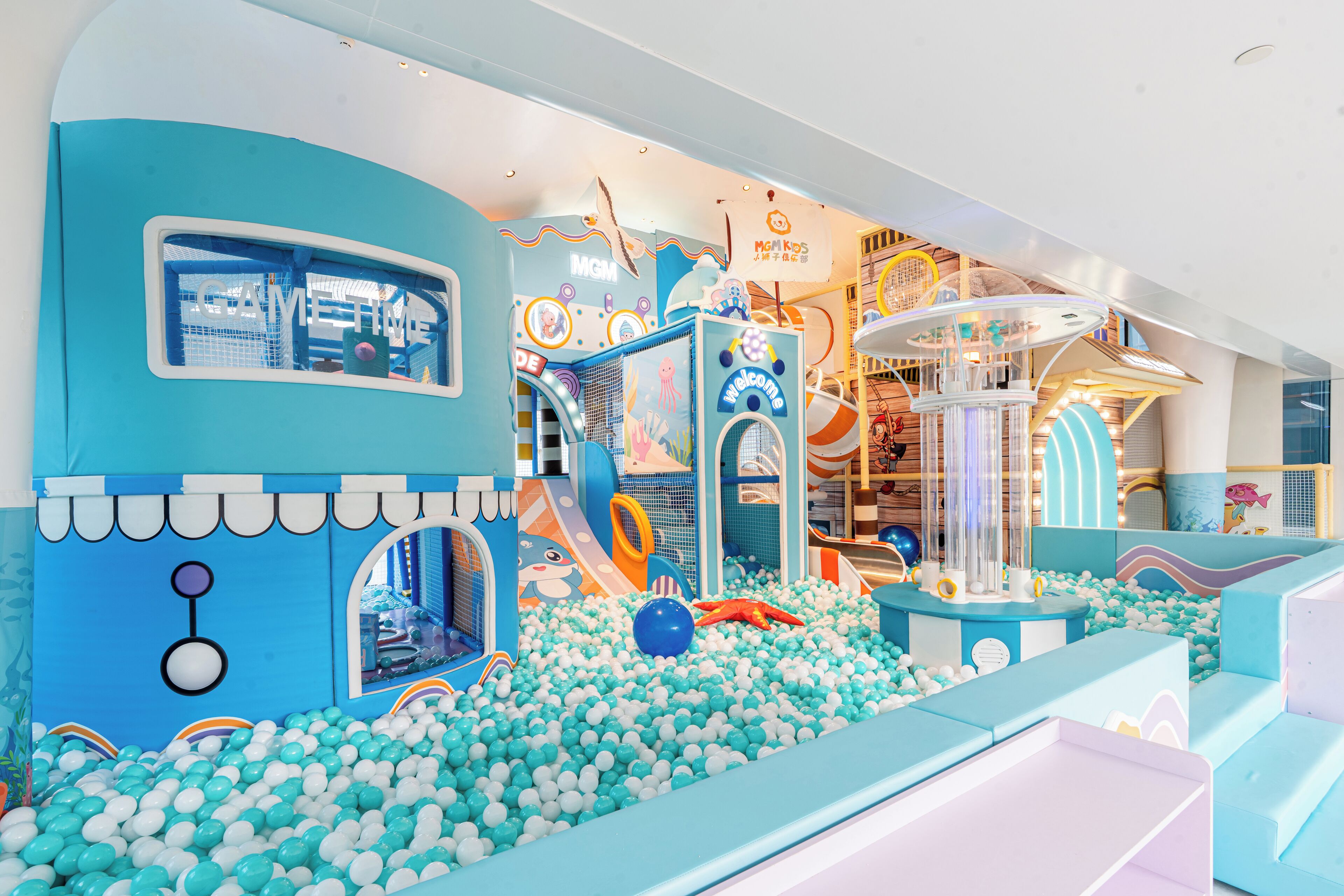 Zona de juegos infantiles con piscina de pelotas, toboganes y estructuras para escalar.