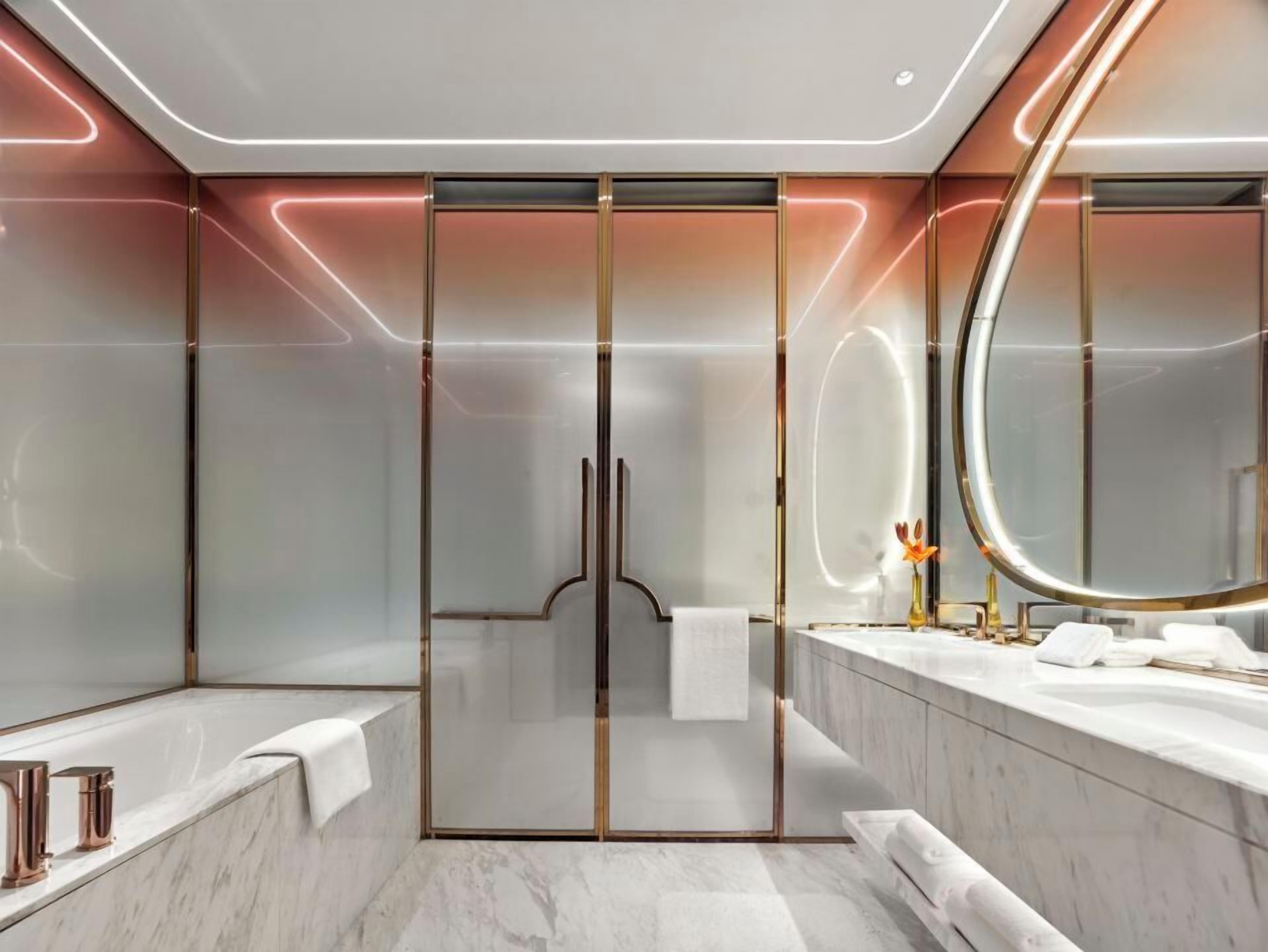 Un baño moderno con cabina de ducha de vidrio, un espejo grande y una encimera de mármol.